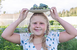 At the dacha, a girl holds fresh green cucumbers in her hands.