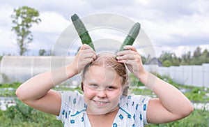 At the dacha, a girl holds fresh green cucumbers in her hands.