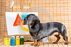 Dachshund artist near easel with its masterpiece