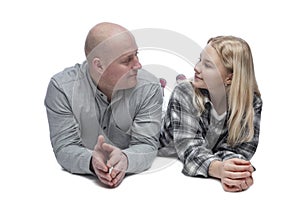 Dad and adult daughter smile and look at each other. A bald man in a gray shirt and a pretty blonde teenager in a black and white