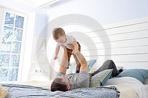 Dad and baby boy playing on bed