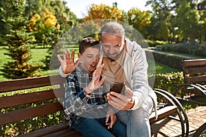 Dad and boy have video call on smartphone on bench