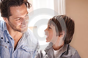 Dad, boy and smile conversation in home, happy son and man bonding for child development and paternal relationship. Kid