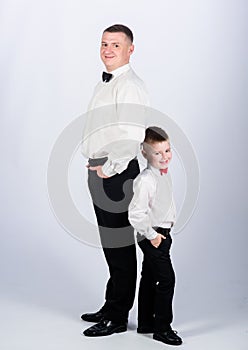 Dad and boy white shirts with bow ties. Gentleman upbringing. Little son following fathers example of noble man