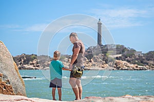 Dad care Son near sea, walk spend time together explore new. Man hold kid hand. Lighthouse background Symbol of