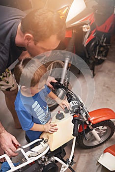 Dad, child and fixing with bike in garage at home for teamwork, support and repair with tools to educate. Family, father