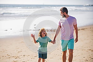 Dad and child having fun outdoors. Father and son walking on sea. Childhood and parenting concept.