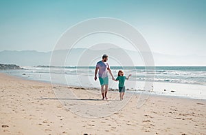 Dad and child having fun outdoors. Father and son walking on summer beach. Dad and child holding hands and walk together