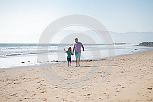 Dad and child holding hands and walk together. Father and son walking on sea. Family travel, vacation, father's day