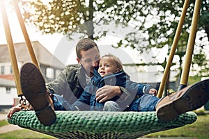 Dad, child and playing together in swing with happy smile, nature and bonding in outdoor garden. Father, son and playful