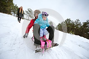 Dad and child sledging in winter on a snowy hill. Happy family
