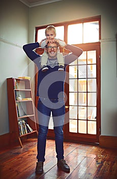 Dad couldnt be happier about bonding with his boy. Portrait of a father carrying his little son on his shoulders at home