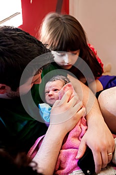 Dad Cradles Newborn Big Sister Looks On