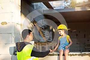 Dad and daughter are at construction site of their future home. The choice of the future profession of a builder is inherited by