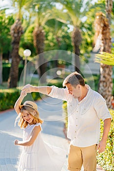 a dad and daughter dance on in a tropical park. attitude of fathers and children