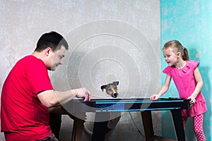 Dad daughter and dog playing air hockey