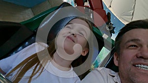 Dad and daughter go on thrill rides in an amusement park.