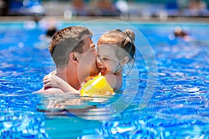 Dad and daughter play and cuddle in the pool.