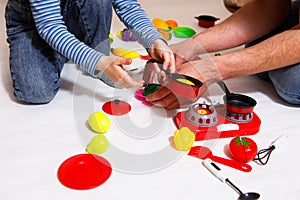 Dad and daughter play with sliced plastic vegetables and fruits with Velcro, cooks food on a toy stove in a bowl. Children`s