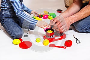 Dad and daughter play with sliced plastic vegetables and fruits with Velcro, cooks food on a toy stove in a bowl. Children`s