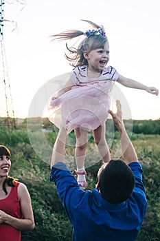 Dad and daughter play together on the flower field. Happy and caring father is having fun with his daughter. Dad pays attention to