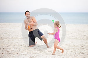 Dad and daughter play water pistols on the sea