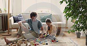 Dad and daughter play wooden bricks toys set at home