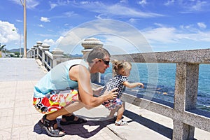 Dad and daughter playing on the promenade by the sea. young man, little girl