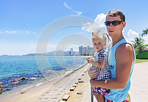 Dad and daughter playing on the promenade by the sea. young man, little girl