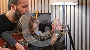 Dad and daughter plays guitar together.Little girl learning guitar with her father at home.Front view.Guitar class at