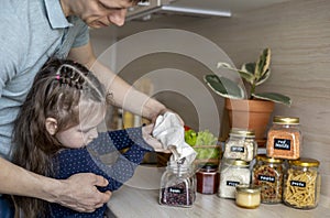 Dad and daughter pour cereal from a reusable bag into a glass jar. Storage in the kitchen