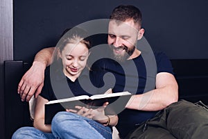 Dad and daughter are reading the Bible book together. Family. A happy child is smiling while sitting on the bed.