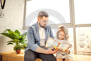 Dad and daughter reading a book at home