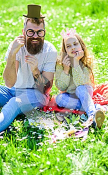 Dad and daughter sits on grass at grassplot, green background. Aristocrates concept. Child and father posing with