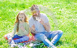 Dad and daughter sits on grass at grassplot, green background. Child and father posing with eyeglases and mustache photo