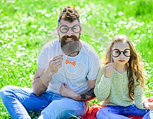 Dad and daughter sits on grass at grassplot, green background. Child and father posing with eyeglases photo booth