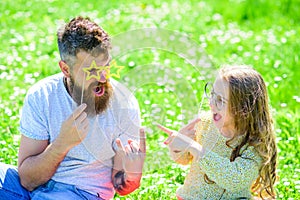 Dad and daughter sits on grass at grassplot, green background. Child and father posing with eyeglases photo booth