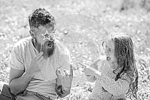 Dad and daughter sits on grass at grassplot, green background. Child and father posing with eyeglases photo booth