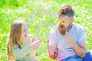 Dad and daughter sits on grass at grassplot, green background. Child and father posing with eyeglases photo booth