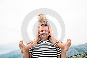 Dad and daughter smiling and having fun together. daughter sitting on dad`s shoulders and covers dad`s eyes with hands.