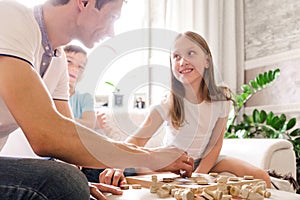 Dad, daughter and son play checkers at home together