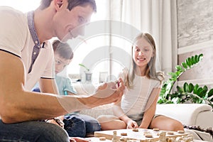 Dad, daughter and son play checkers at home together