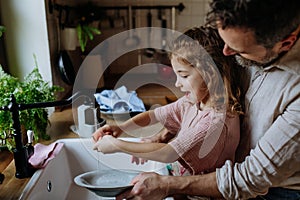 Dad and daughter washing dishes in sink together. Girls dad. Unconditional paternal love, Father& x27;s Day concept.