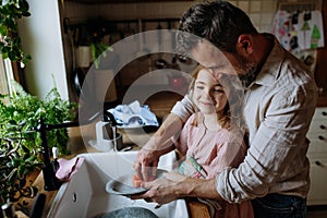 Dad and daughter washing dishes in sink together. Girls dad. Unconditional paternal love, Father& x27;s Day concept.