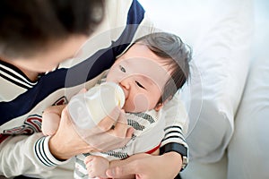 Dad feeding her baby daughter infant from bottle Adorable baby with a milk bottle