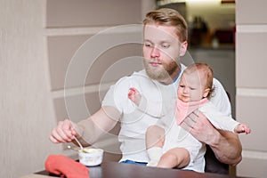 Dad feeds his naughty baby who refuses to eat fruit puree