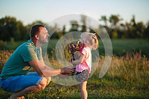 Dad gives his daughter flowers at sunset