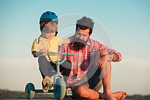 Dad help his child ride a bicycle. Lovely father teaching son riding bike.