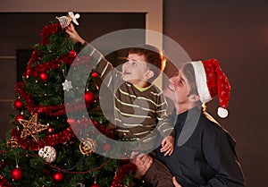 Dad helping boy to decorate christmas tree photo