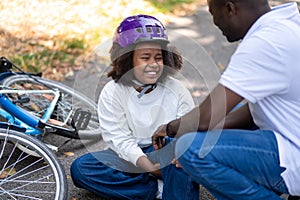 Dad helping his son after falling down from a bike